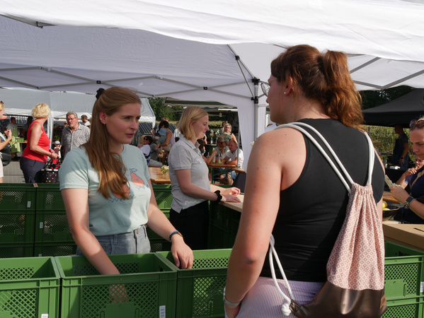 KI generiert: Frau mit Gemüse feiert 10 Jahre Biobote; Hallenfest am 06.09. in Haren. Text: "Wir feiern 10 Jahre Biobote..."