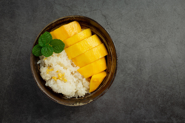 KI generiert: Eine Schale mit Mango und Klebreis, garniert mit einem Minzzweig.