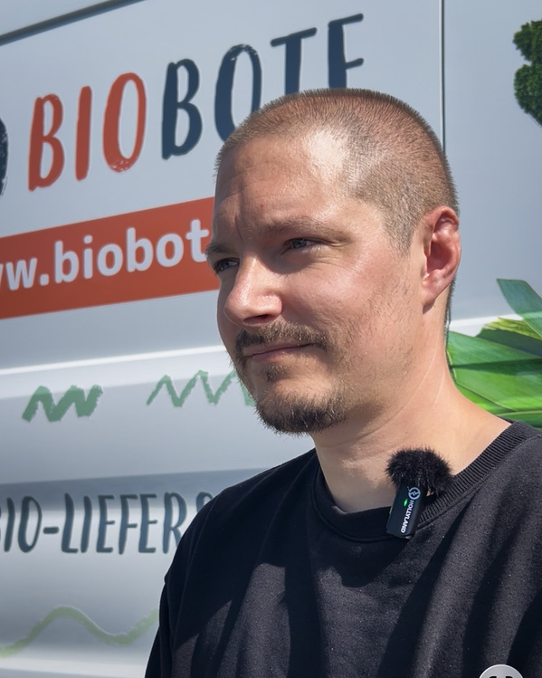 Sebastian Bosse vor einem Lieferfahrzeug der Marke "BIOBOTE". Text: "www.biobote.de".