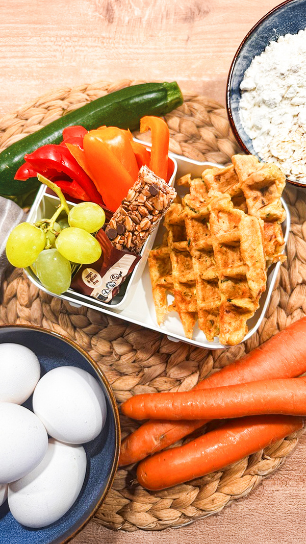 KI generiert: Verschiedene Lebensmittel inklusive Waffeln, Gemüse, Eiern und Müsli-Riegel auf einem Tisch arrangiert.
