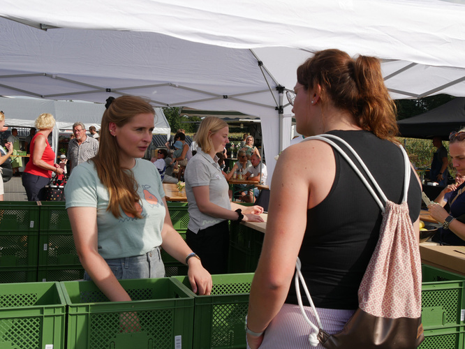 KI generiert: Frau hält Gemüse, Feier für 10 Jahre Biobote am 06.09. in Haren mit Bio-Snacks, Musik und Programm.