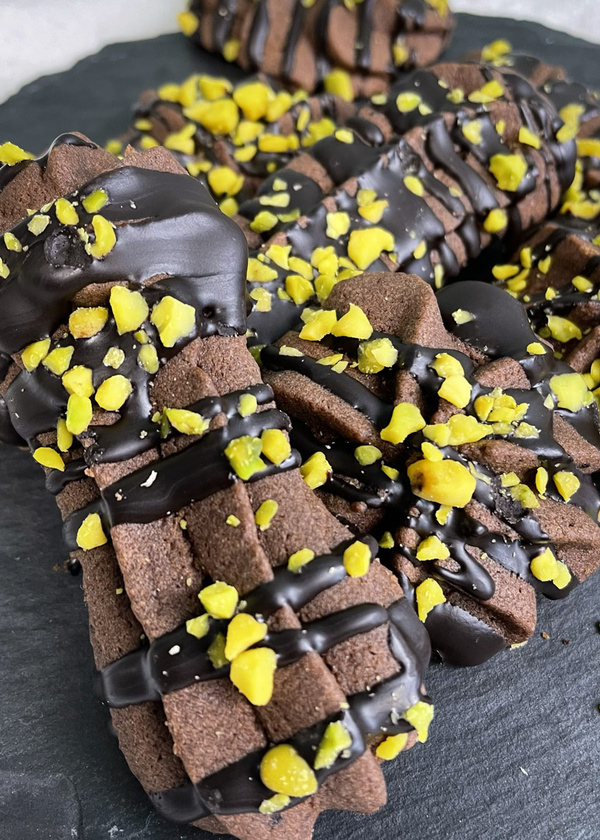 KI generiert: Schokoladenkekse mit Schokoglasur und gelben Streuseln auf einer Schieferplatte.