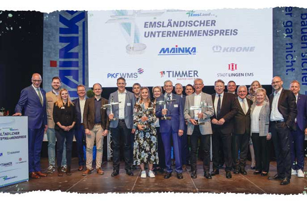 Eine Gruppe von Personen posiert auf einer Bühne mit dem Text "EMSLÄNDISCHER UNTERNEHMENSPREIS".