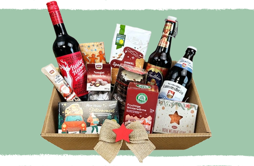 KI generiert: Ein Geschenkkorb mit Getränken und Weihnachtssüßigkeiten auf grünem Hintergrund.