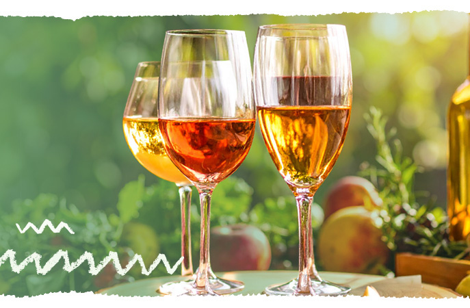 KI generiert: Drei Weingläser mit roséfarbenem Wein im Freien zwischen Pflanzen und Früchten.