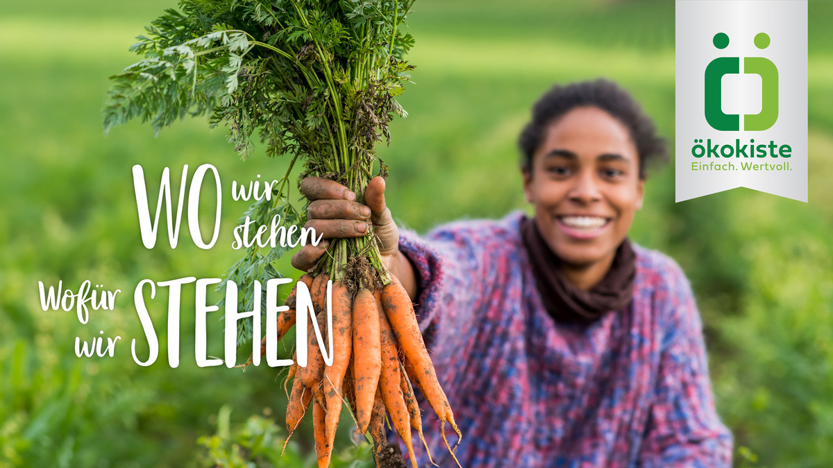Eine Person hält frische Karotten; Text: "WO wir stehen, Wofür wir STEHEN". Logo: Ökokiste, Einfach. Wertvoll.