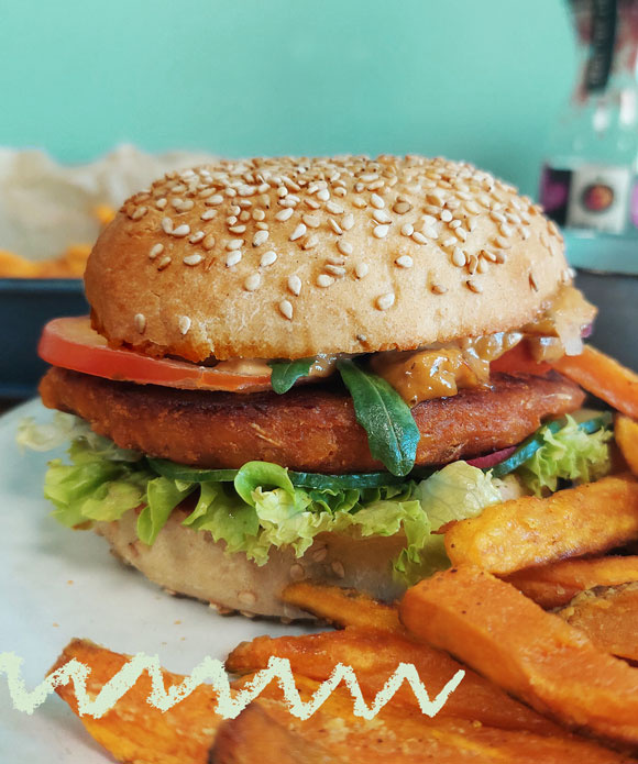 KI generiert: Ein Hamburger mit Gemüse und Süßkartoffelpommes auf einem Teller.