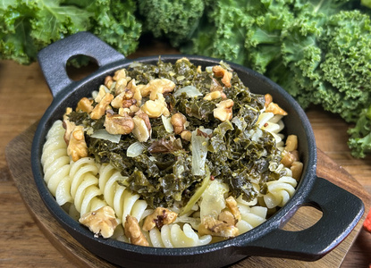 KI generiert: Das Bild zeigt ein Glas mit cremiger Suppe, garniert mit schwarzen Sesamsamen und orangen Stücken, daneben liegen Brotscheiben und verschiedene frische Gemüsearten wie Blumenkohl und Süßkartoffeln. Es vermittelt einen rustikalen, gesunden Eindruck.