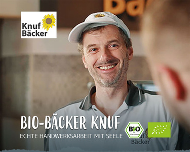  Bäcker Markus Knuf mit Kappe lächelt. Text: "BIO-BÄCKER KNUF ECHTE HANDWERKSARBEIT MIT SEELE."