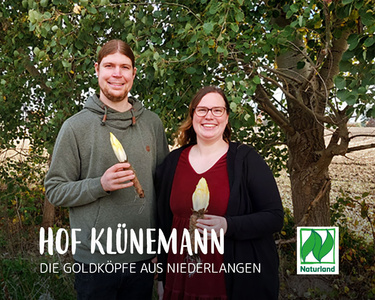 n Mann und eine Frau präsentieren Chricorée vor Bäumen. Text: "Hof Klünemann – Die Goldköpfe aus Niederlangen".