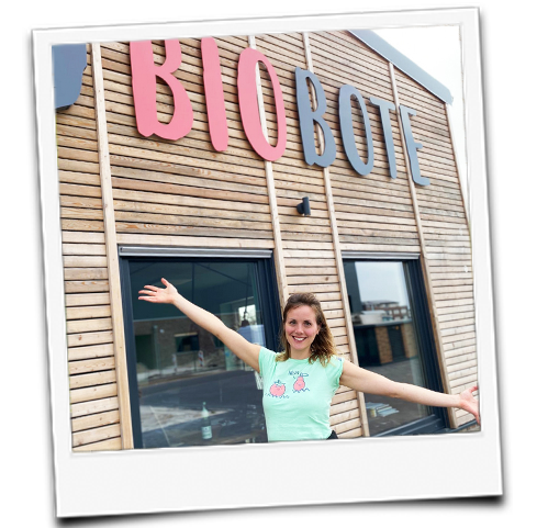 KI generiert: Person lächelt vor einem Gebäude mit der Aufschrift "BIOBO".