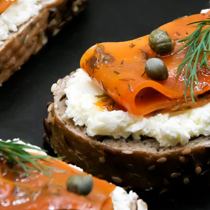 KI generiert: Vollkornbrot mit Frischkäse, Lachs, Kapern und Dill garniert.