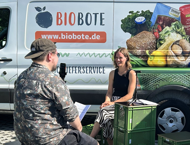 Nik und Lisa sitzen zum Interview vor Bioboten bulli