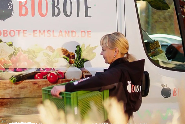 Bioboten Bulli, davor Fahrerin mit grüner Biokiste