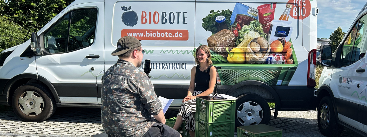 KI generiert: Eine Frau wird vor einem Lieferwagen von "BIOBOTE" gefilmt. Text: "BIOBOTE www.biobote.de".