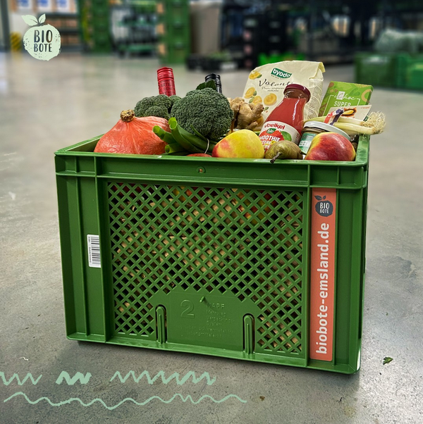 KI generiert: Grüne Kiste mit Bio-Lebensmitteln, inklusive Obst und Gemüse. Text: "biobote-emsland.de".