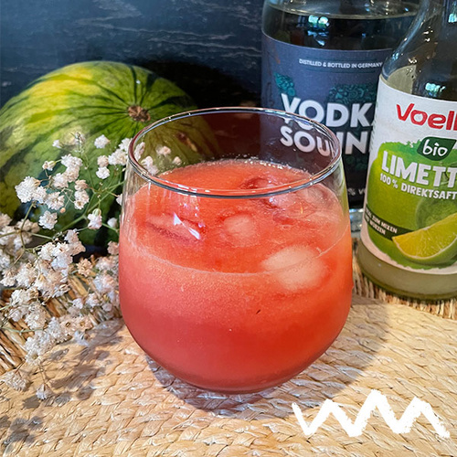 KI generiert: Ein Getränk im Glas mit Eis, umgeben von einer Limettensaftflasche und einer Vodkaflasche.